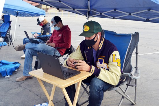 Lemoore High School students gather Monday morning in student parking lot advocating for early return to school Lemoore High School's Janson Cunningham (working on a laptop) and others want to return to school and protested the district's decision to fully open by January.
